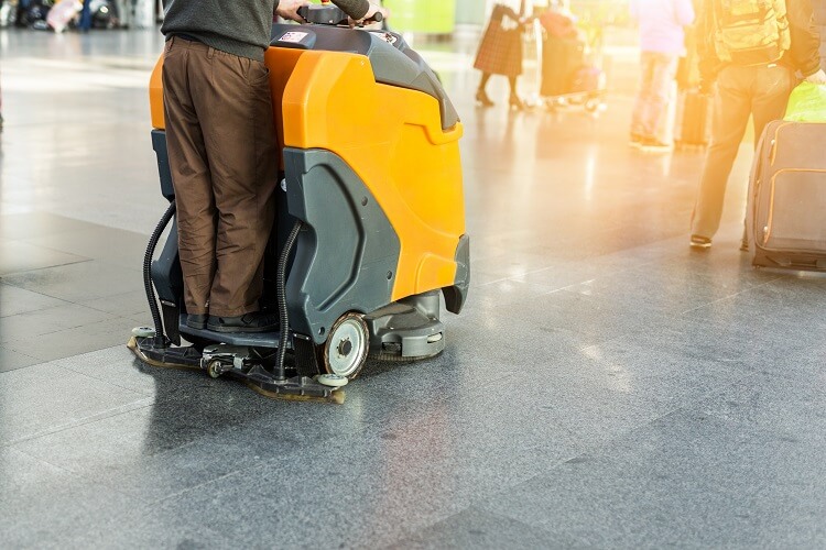 Day porter using floor equipment in a commercial building during his cleaning service